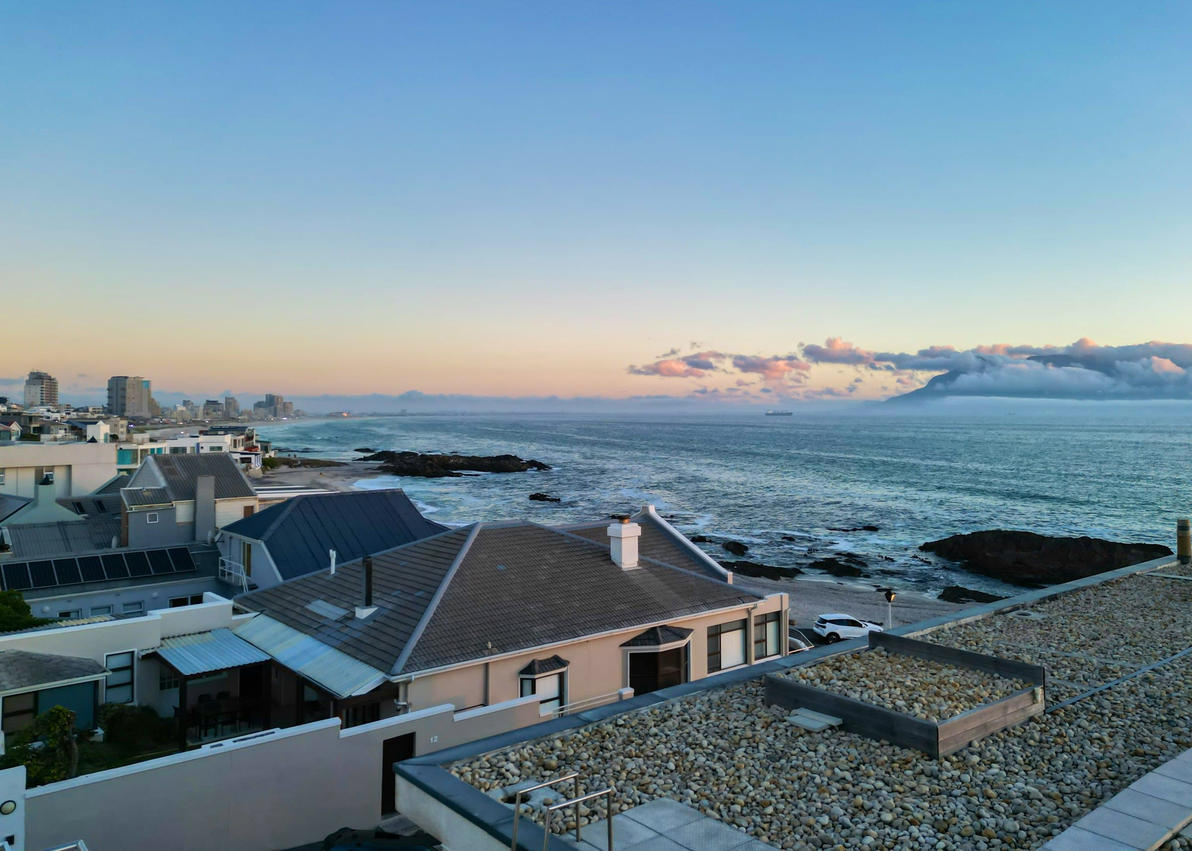 Coastal rooftops and shoreline with Table Mountain across the bay