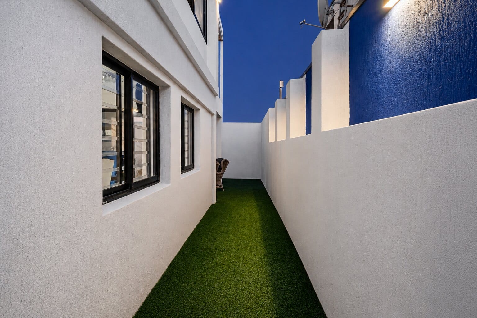 A cobalt-blue wall beside a grass path at The Lighthouse during blue hour