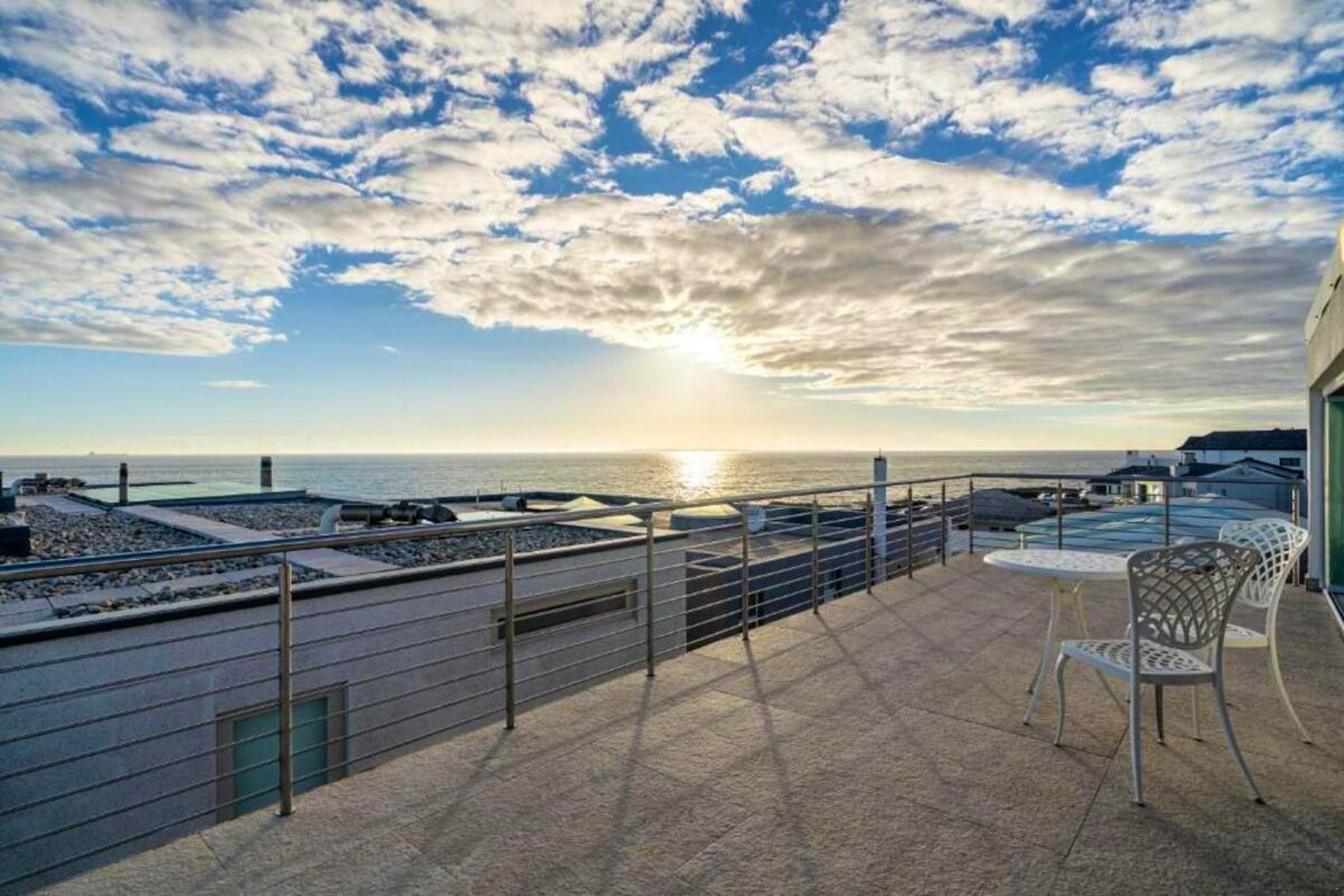 Ocean-facing terrace at The Lighthouse with outdoor chairs beneath a clouded sky